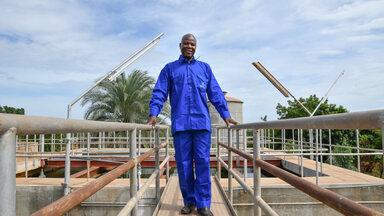 Man in blue uniform at a water system in West Africa