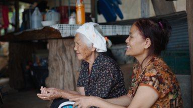 Happy caregiver assisting and sharing a tender moment with her elderly mother in a low income household