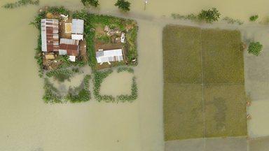 Aerial view of Sunamganj Haor showing houses surrounded by floodwaters and submerged rice fields in the rural landscape of Sunamganj District, Sylhet Division, Bangladesh