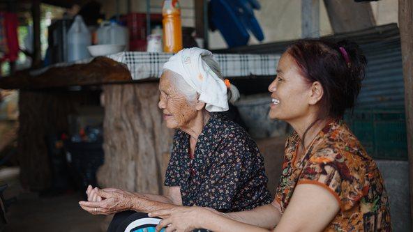 Happy caregiver assisting and sharing a tender moment with her elderly mother in a low income household