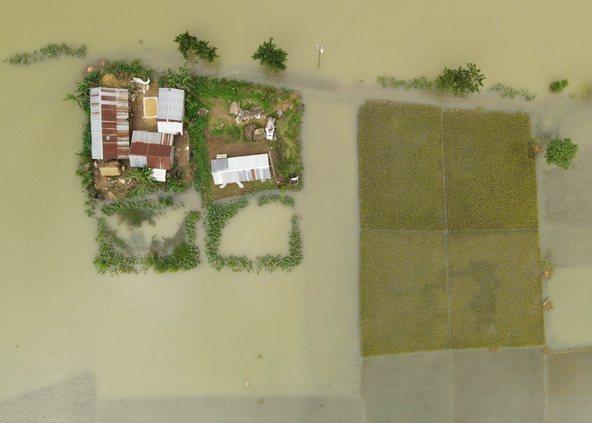 Aerial view of Sunamganj Haor showing houses surrounded by floodwaters and submerged rice fields in the rural landscape of Sunamganj District, Sylhet Division, Bangladesh