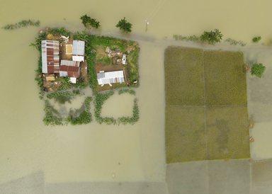 Aerial view of Sunamganj Haor showing houses surrounded by floodwaters and submerged rice fields in the rural landscape of Sunamganj District, Sylhet Division, Bangladesh