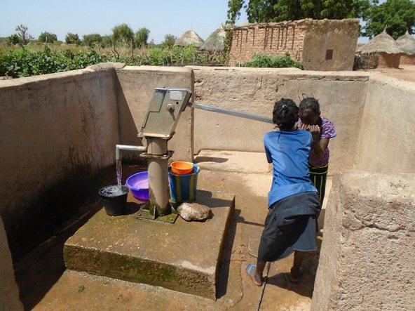 Deux jeunes filles qui prélèvent de l'eau au niveau d'une pompe à motricité humaine dans un village de la commune de Makalondi, 2020. Crédit photo : IRC WASH